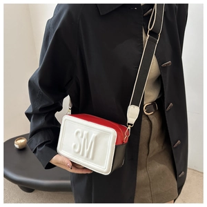 Detail of tricolor camera bag with embossed letters and striped canvas strap