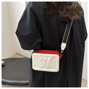Close-up of contrast crossbody bag with embossed SM logo and wide fabric strap
