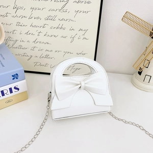 Detail of white PU leather mini bag featuring a large bow and silver chain strap