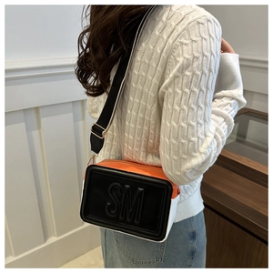 Detail of tricolor crossbody bag with wide strap and embossed SM lettering on front