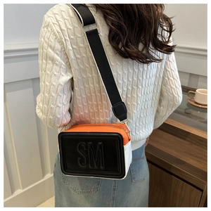 Detail of crossbody bag with wide shoulder strap and SM embossed logo on a camera bag
