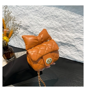 Detail of bright orange quilted bag with large bow and golden metal twist lock