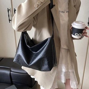 Minimalist black large capacity hobo shoulder bag shown on model in urban commute setting