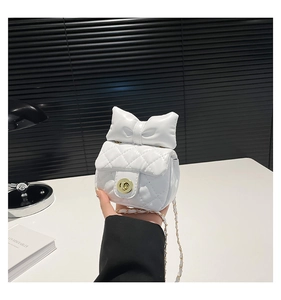 Detailed close-up of white quilted mini bag with oversized bow and gold twist lock