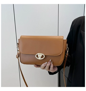 Détail du sac bandoulière en similicuir caramel avec boucle en V dorée et coutures précises