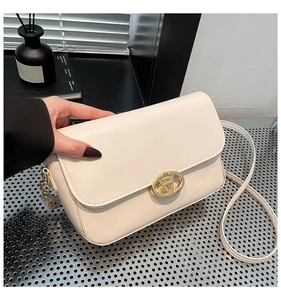 Détail du sac bandoulière en cuir PU crème avec un fermoir rotatif ovale en métal doré