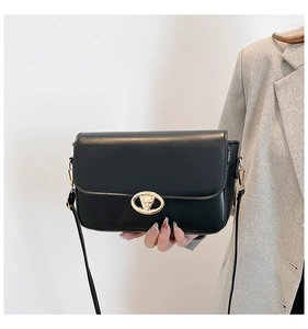 Détail du sac en cuir noir mat avec boucle dorée et fine bandoulière réglable