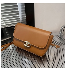 Détail du sac à bandoulière en cuir caramel avec un fermoir rond en métal doré