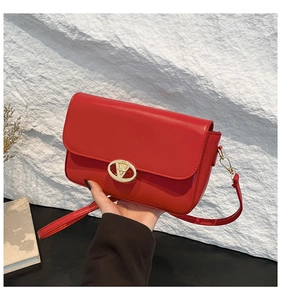 Détail du sac rouge présentant un fermoir rond doré avec boucle en forme de V chic