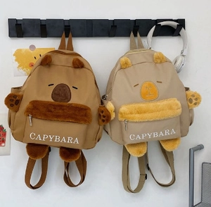 Detail of cute capybara plush pocket and ears on canvas backpack with logo text