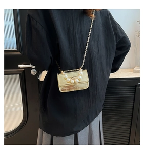 Model wearing a gold crocodile pattern mini bag with pearl handle and chain strap