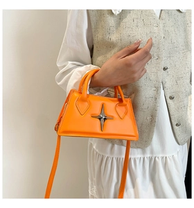 Détail du sac bandoulière orange vif avec boucle étoile en métal 3D et bandoulière en cuir