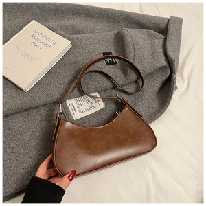 Gros plan d'un sac sous le bras en forme de lune marron rétro sur un manteau en laine