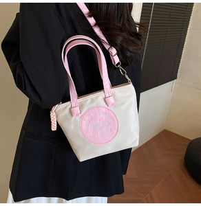 Détail d'un sac bandoulière contrasté crème et rose avec bandoulière réglable