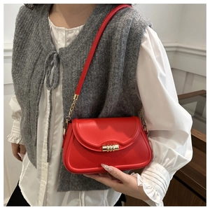 Close-up of red leather crossbody bag with elegant gold multi-ring buckle and metal chain