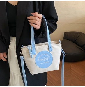 Détail d'un sac seau beige minimaliste avec anses bleues dans un intérieur élégant