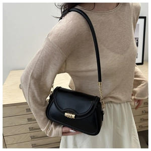 Detail of a black underarm bag with gold cylindrical lock and chain link leather strap