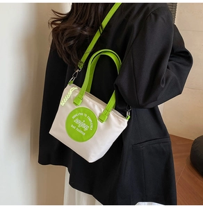 Sac fourre-tout en toile blanche avec anses vert fluo porté en bandoulière par un modèle