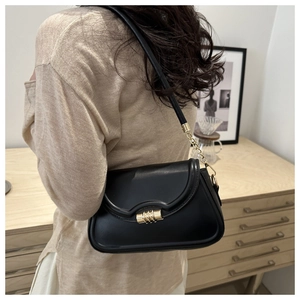 Detail of minimalist black leather crossbody bag featuring a golden spiral lock closure