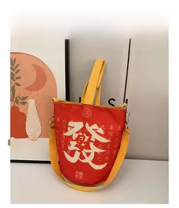 Detailaufnahme der roten Segeltuchtasche mit weißer Kalligraphie und gelben Tragegriffen