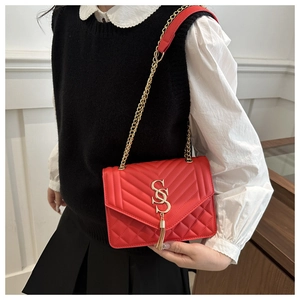 Detail of red quilted crossbody bag with gold SS logo and elegant tassel charm