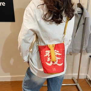 Detail einer roten Segeltuchtasche mit chinesischer Kalligraphie und gelbem Gurt