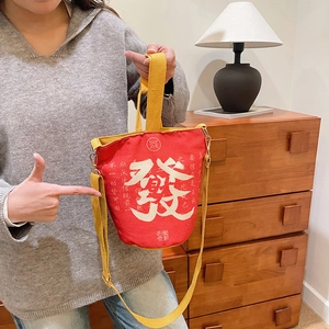 Detail der roten Canvas-Beuteltasche mit Gold-Fa-Zeichen und gelbem Gurtband