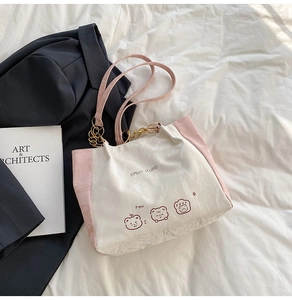 Flat lay of cream and pink tote bag with bear print on stylish white fabric background