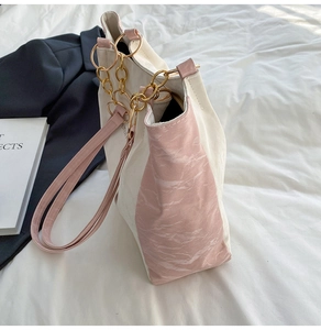 Detail of color-block tote bag featuring marble accents and gold ring chain handles