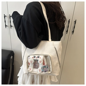 Detailed side view of white tote bag with clear window showing plush bunny and badge