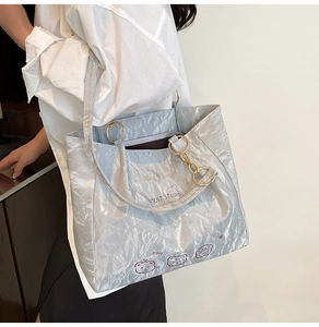 Detail of silver metallic tote bag featuring pleated texture and cute bear illustration