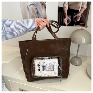 Detail of dark brown tote bag with transparent front pocket and plush cat charm