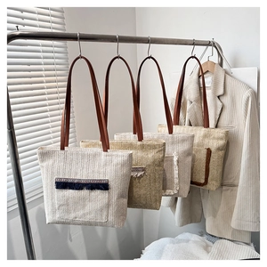 Detalle de cuatro bolsos tote de paja trenzada con borlas y correas de cuero