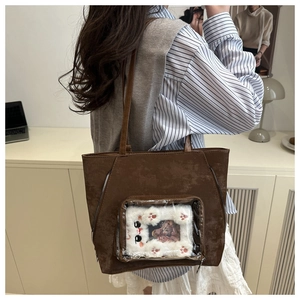 Detail of dark brown tote bag with large transparent window and plush cat paw charm