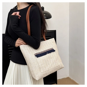 Detalle del bolso tote de paja trenzada con bordado étnico y borlas de flecos azules