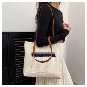 Detalle de bolso tote de paja trenzada con borlas azules y bordados étnicos