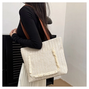 Detalle del bolso tote tejido con bolsillo de flecos y correas de cuero marrón