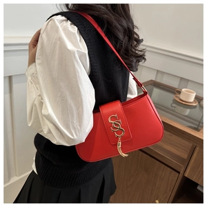 Detail of red crescent shoulder bag with gold metal logo and tassel on elegant model