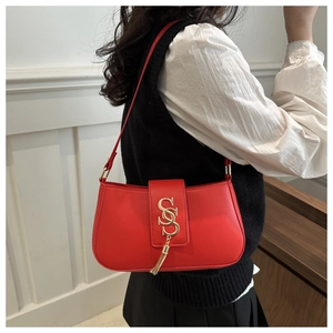 Detail of red faux leather crescent bag with gold SS buckle and metallic tassel accents