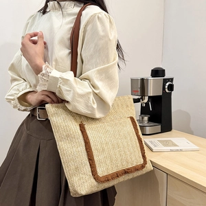 Bolso capazo de paja con asas de cuero marrón y bolsillo frontal decorativo