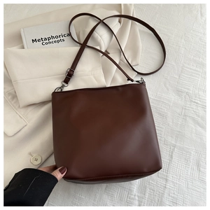 Detailed overhead view of a deep brown bucket bag styled on a white blazer with a book