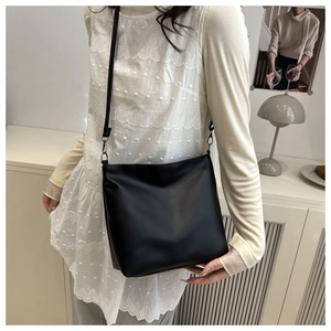 Close-up of a black minimalist bucket bag with thin straps in a home setting
