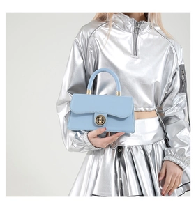 Detail of light blue leather handbag with golden round twist lock and smooth texture