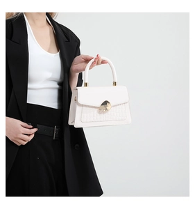 Close-up of white leather handbag with golden metal buckle and faux crocodile texture