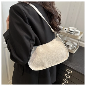 Close-up of white croissant bag with crocodile pattern texture on a black blazer