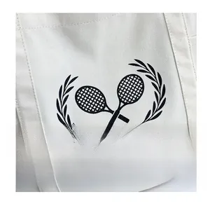 Detail of cream canvas tote bag featuring a black tennis racket print and stitching