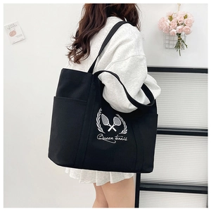 Side view of a large black canvas tote bag with Queen Tennis print on a model