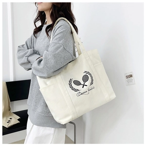 Side view of large canvas tote bag with Queen tennis print shown on model's shoulder
