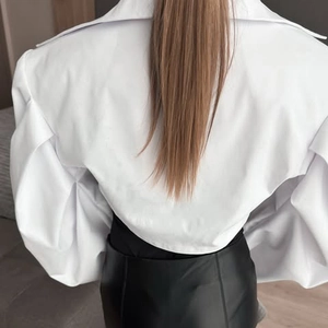 Détail d'un chemisier blanc à manches longues avec manches bouffantes et poignets pliés