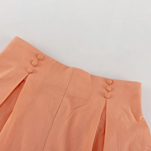 Detail der korallenrosa Taille mit dekorativen Knöpfen und gefalteter Stoffstruktur